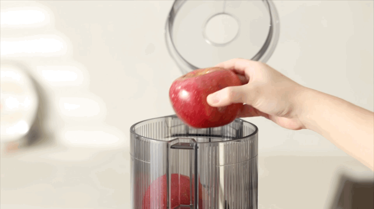 The Hurom H80 self-feeding hopper being filled with fresh produce